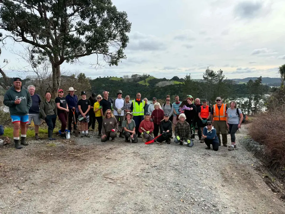 A large group of volunteers on a gravel road above Huawai Bay
